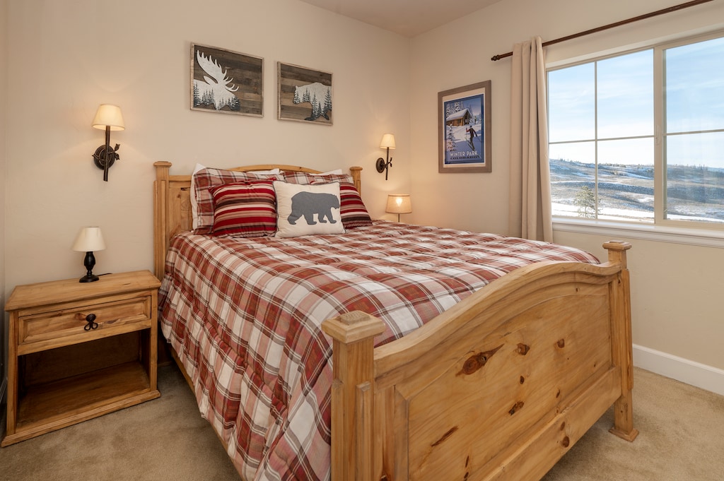 - Rustic bedroom with plaid bedding and mountain decor   - Comfortable queen bed for restful nights after adventure   - Window views highlight Winter Park alpine landscape