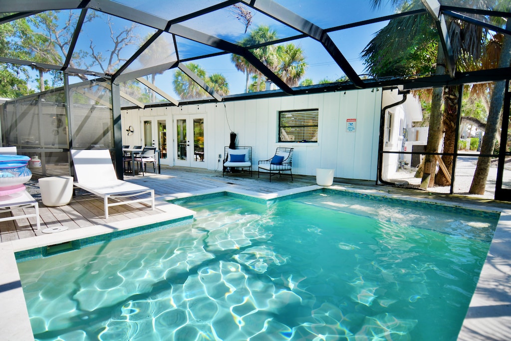 Outdoor patio area with a screened-in pool, seating and loungers