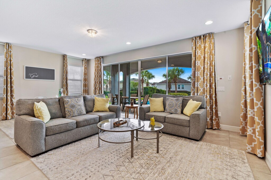 Step into a cozy retreat in inviting living area of the home in Kissimmee Florida - Natural light floods the room, enhancing its warmth and inviting atmosphere - Easy access to outdoors with pool and outdoor dining via sliding glass door