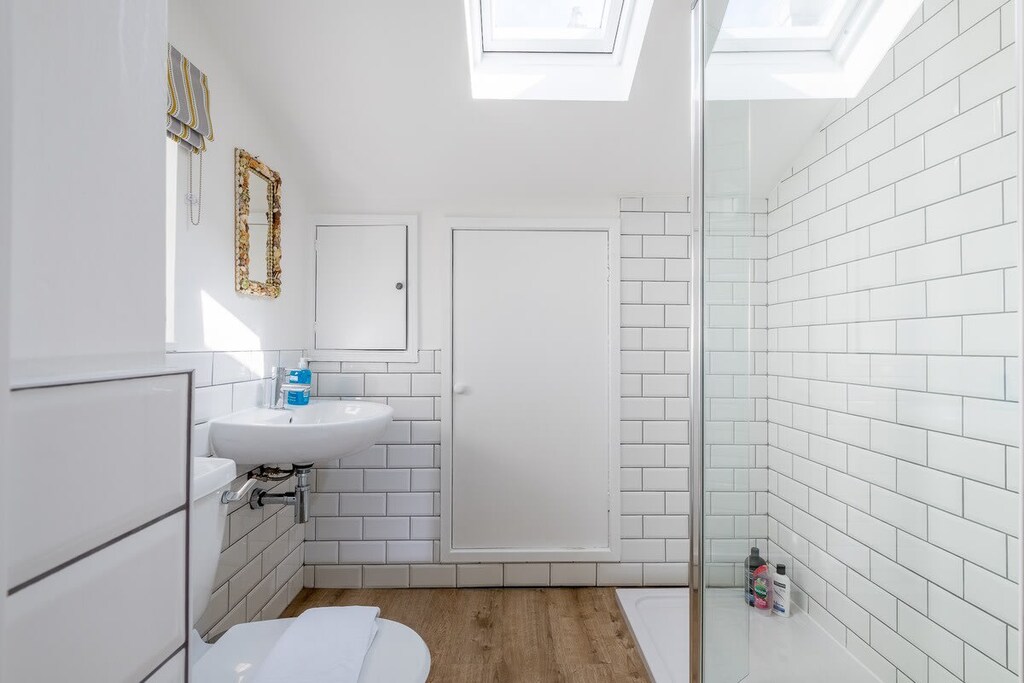 The modern white bathroom has a walk-in shower, toilet and basin and Velux windows that let in plenty of natural light.