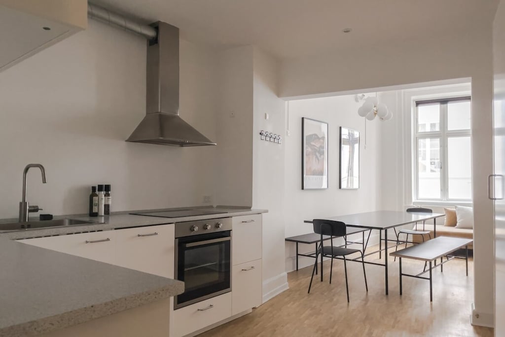 The open-plan kitchen boasts a modern, sleek design with a focus on clean lines and minimalist aesthetics. The use of white as the primary color scheme creates a bright and airy atmosphere, reflecting natural light that pours in from nearby windows.