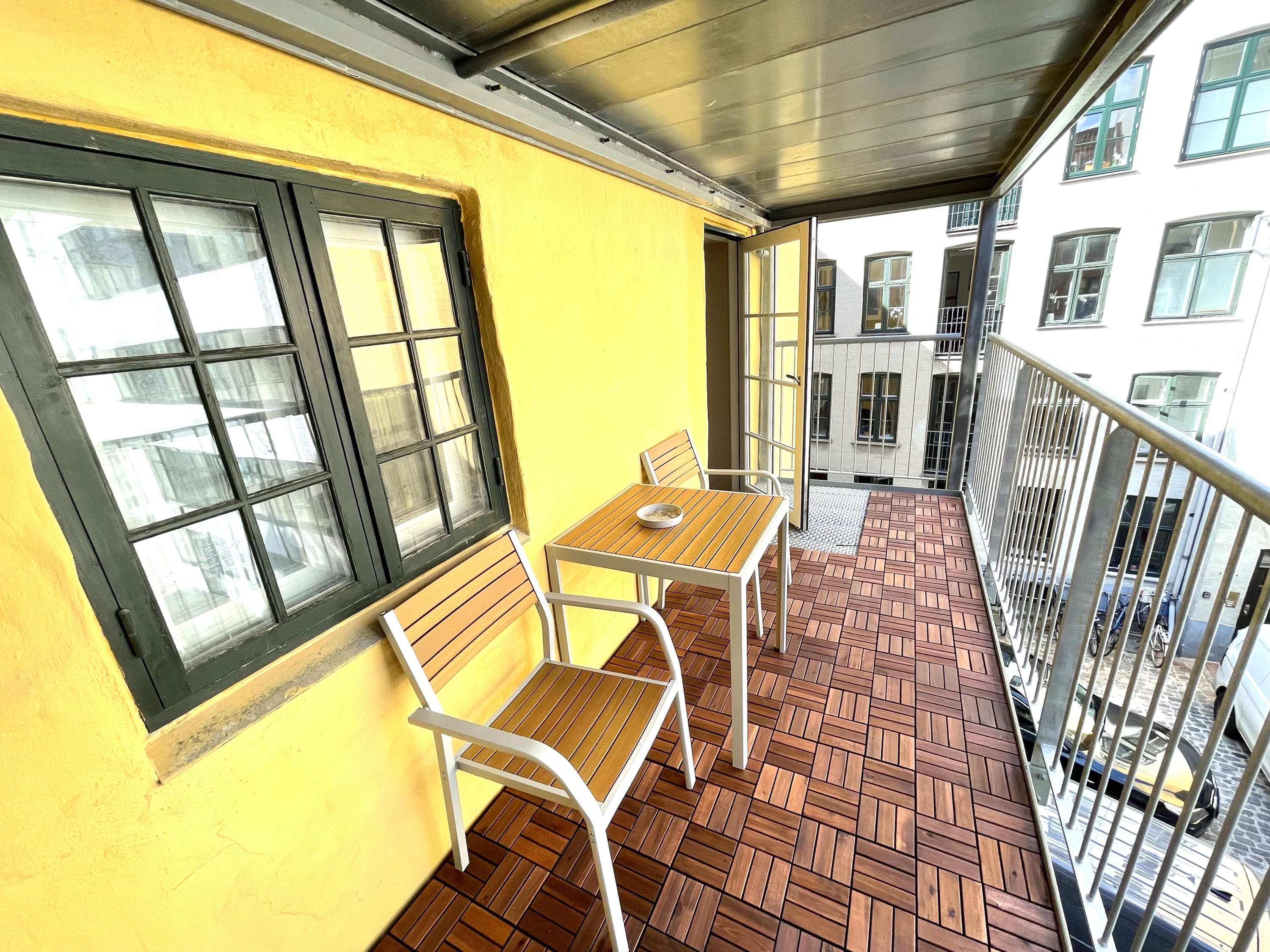 Spacious balcony with two chairs and a table.