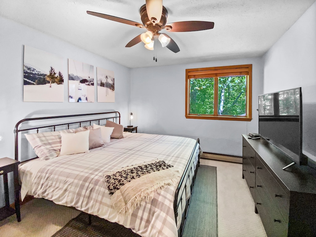 - King bedroom with ceiling fan dresser and window view - Cozy plaid bedding adds mountain charm to the room - Relaxing retreat for families on ski or summer getaways