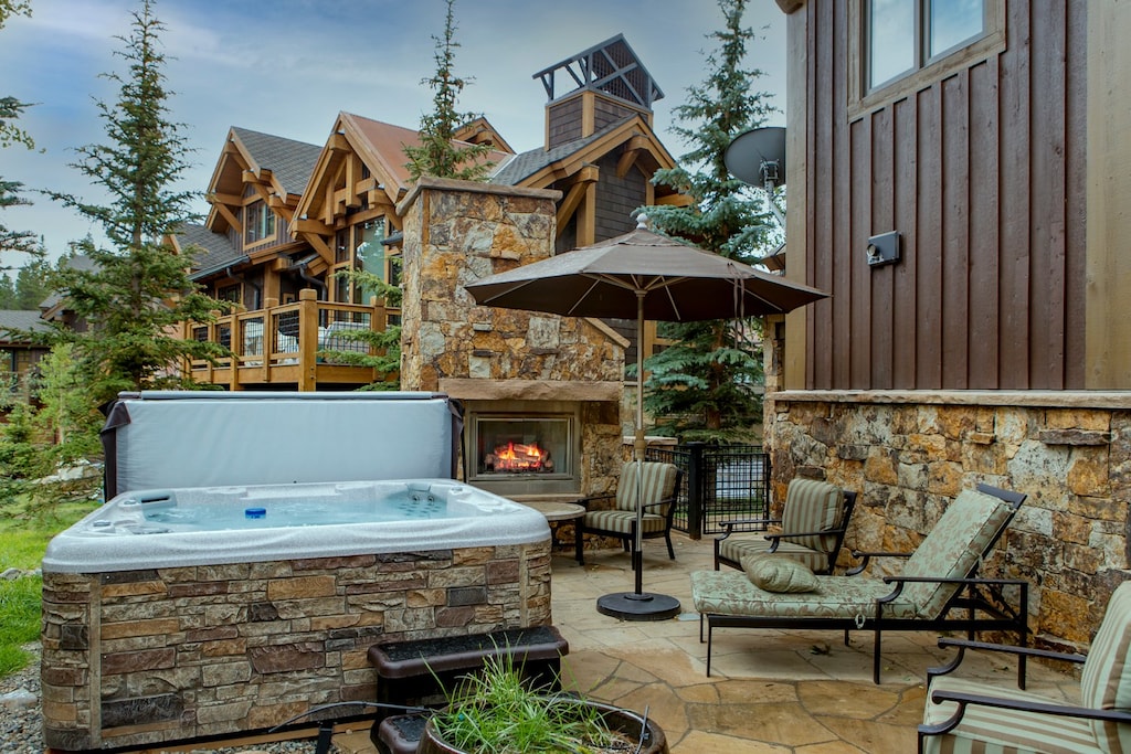 back patio accessed from the living room, large hot tub, lounge chairs, fireplace, and grill!