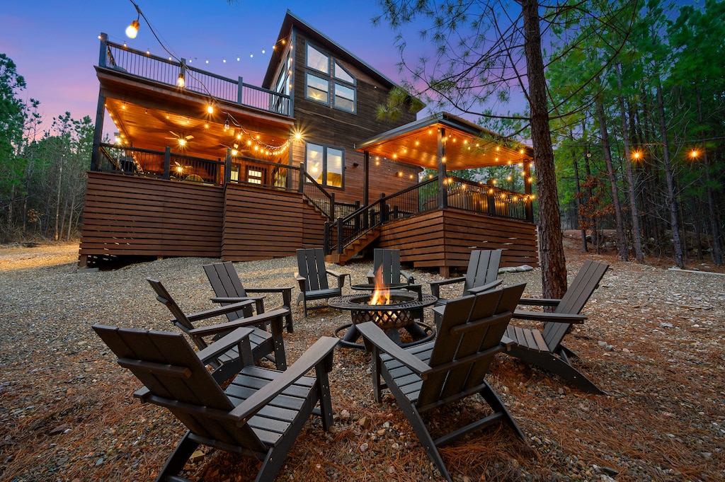 Outdoor firepit with adirondack chairs, string lighting and the back of the Counting Stars cabin in the background.