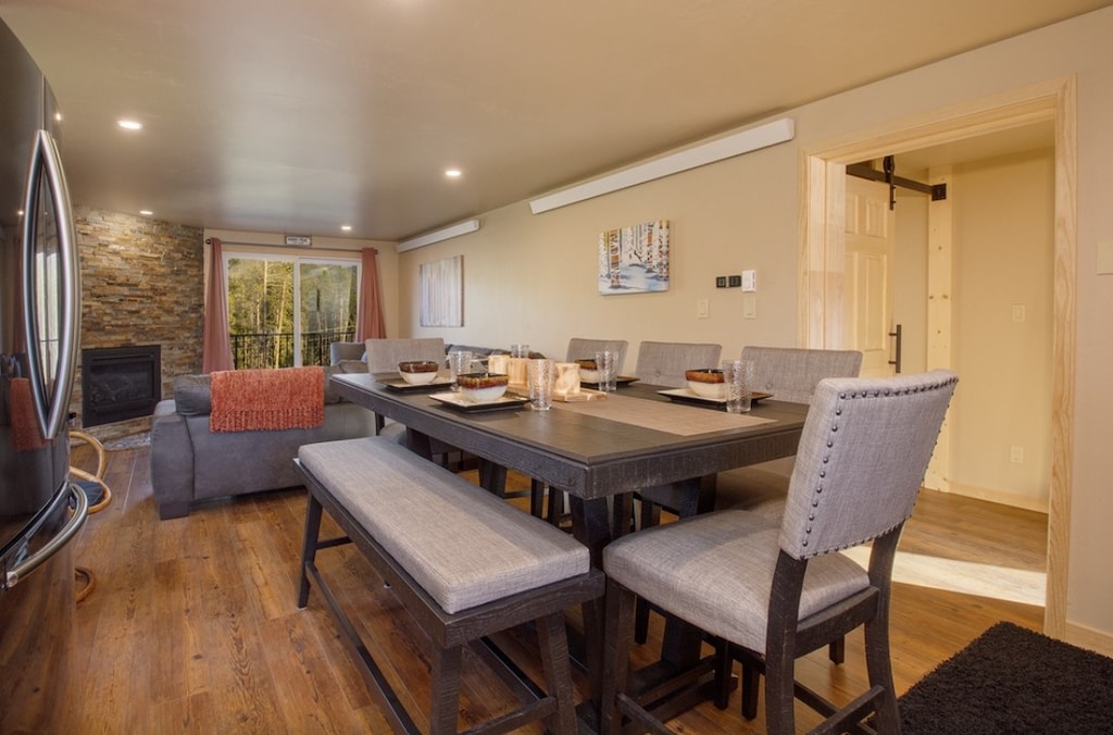 Gather around your elegant dining table where memorable meals unfold, with warm wood floors and mountain views creating the perfect backdrop.