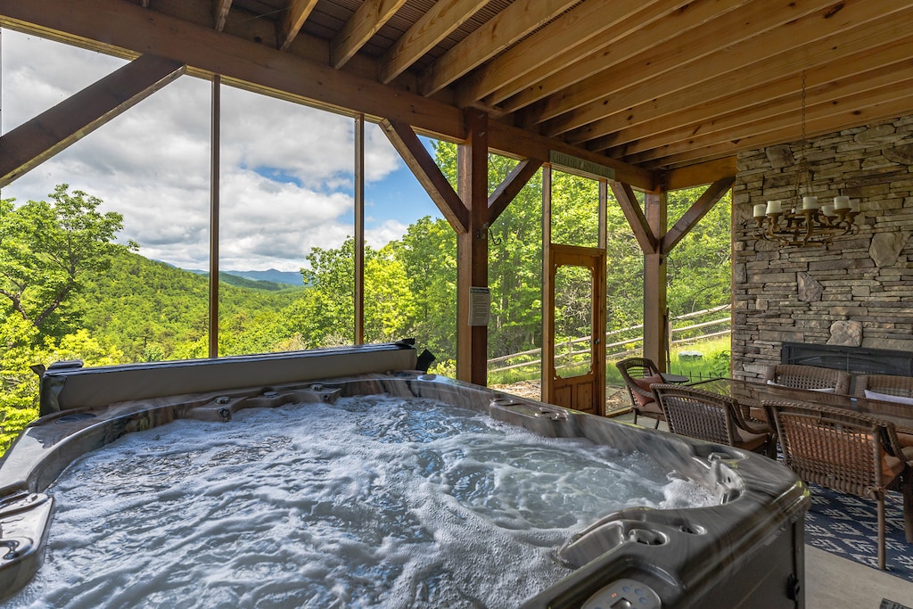 Lower level screened-in porch with outdoor dining for 6, hot tub, and access to the backyard with traditional fire pit. Please note: this fireplace is NOT operational.