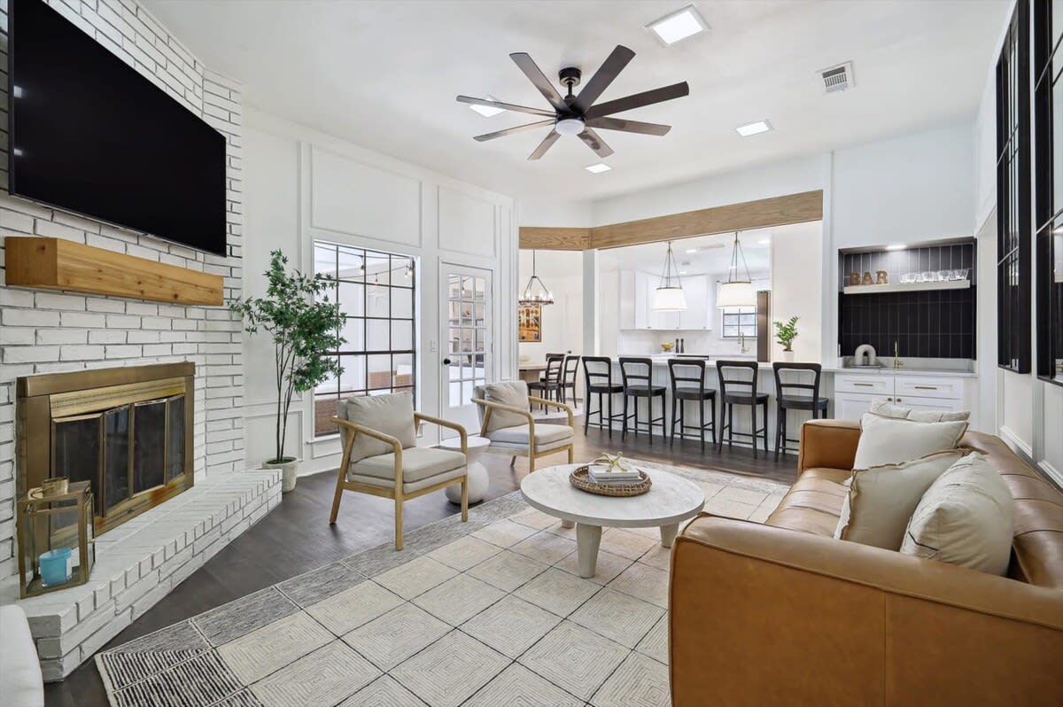 Featuring wooden accents, a cozy fireplace, and detailed paneling, this sophisticated living room is a prime place to gather around to watch your favorite shows or catch up with old friends.