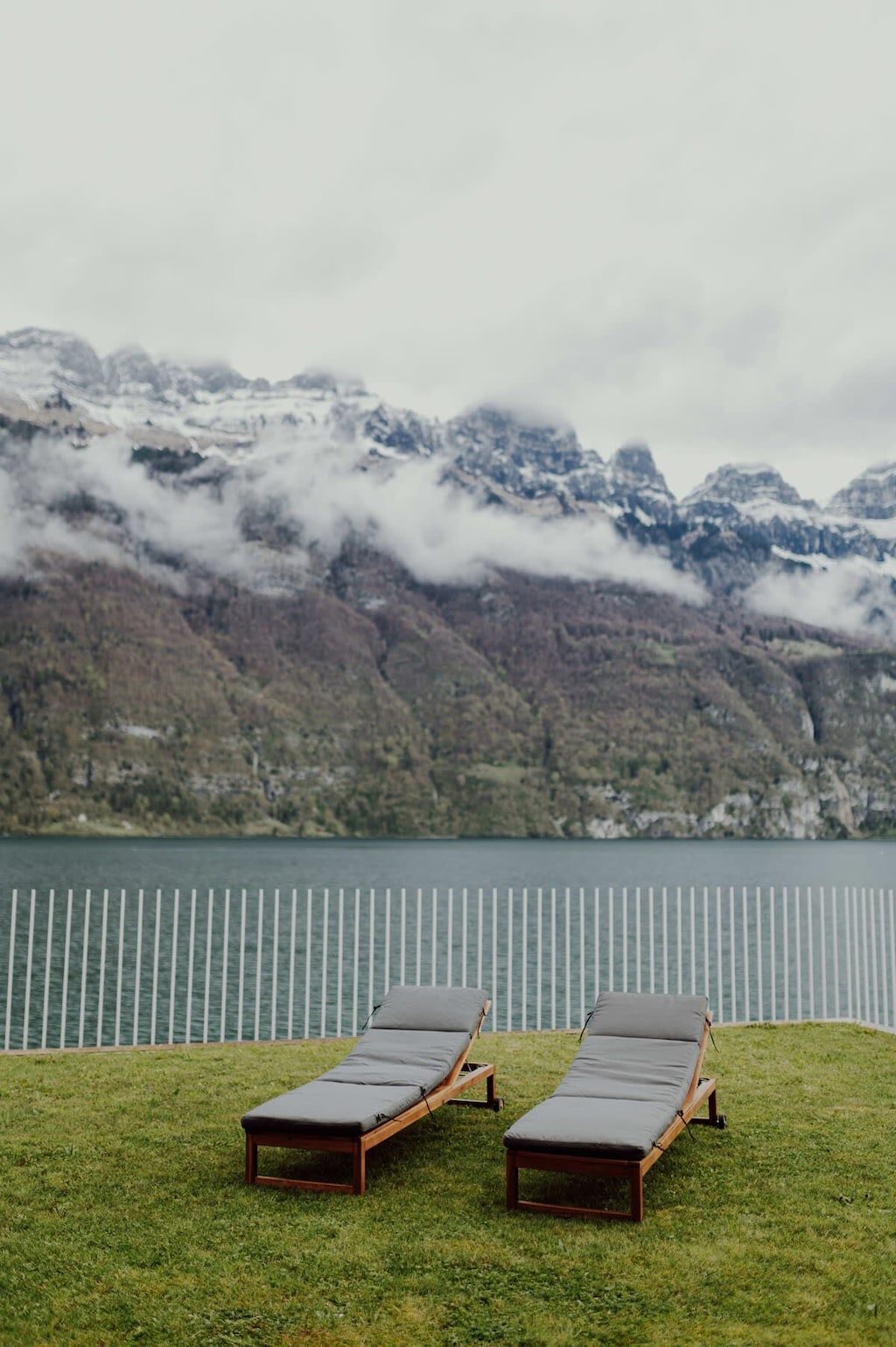 
Recline on a sun lounger and take in the awe-inspiring view of a misty mountain range reflected in a serene lake.