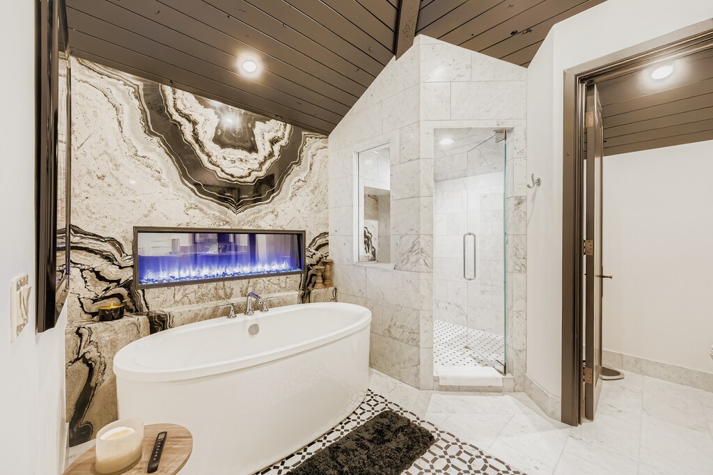 Indulge in pure luxury with your own spa-like retreat featuring a stunning soaking tub, elegant marble finishes, and a sleek fireplace for ultimate relaxation.