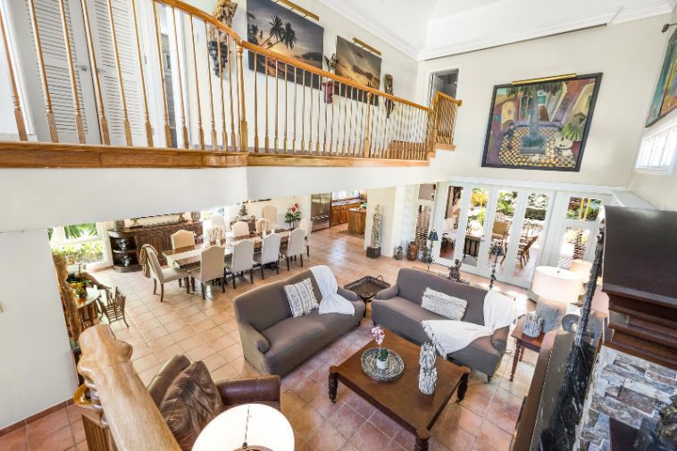Look down from the staircase landing onto this open-design large space, with inter-leading living and dining areas – both under a vaulted ceiling – with its vaulted walls adorned with large, contemporary wall art.