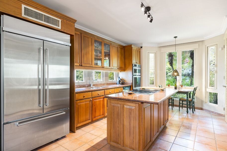 Remodeled kitchen with new appliances. A center island – housing the built-in stovetop – under a large, Tiffany style light fitting. In the distance you can see the large dining room table that seats up to ten guests. Remodeled kitchen with new appliances. A center island – housing the built-in stovetop – under a large, Tiffany style light fitting. In the distance you can see the large dining room table that seats up to ten guests.