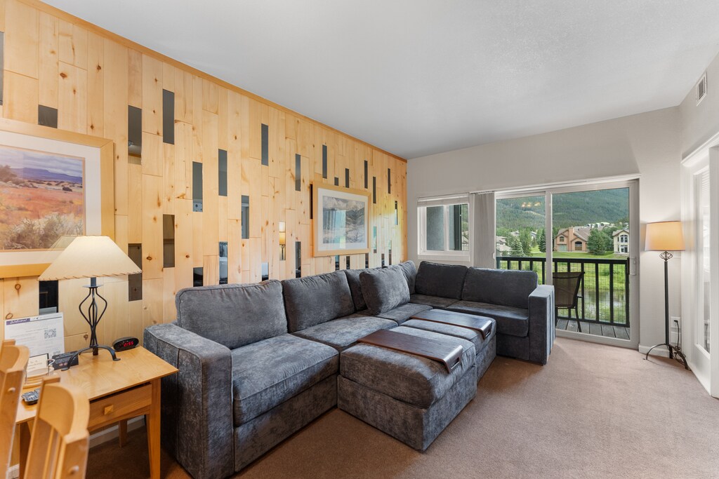 Living room featuring a queen size sleeper sofa, flat screen TV, and balcony access to incredible mountain views. 