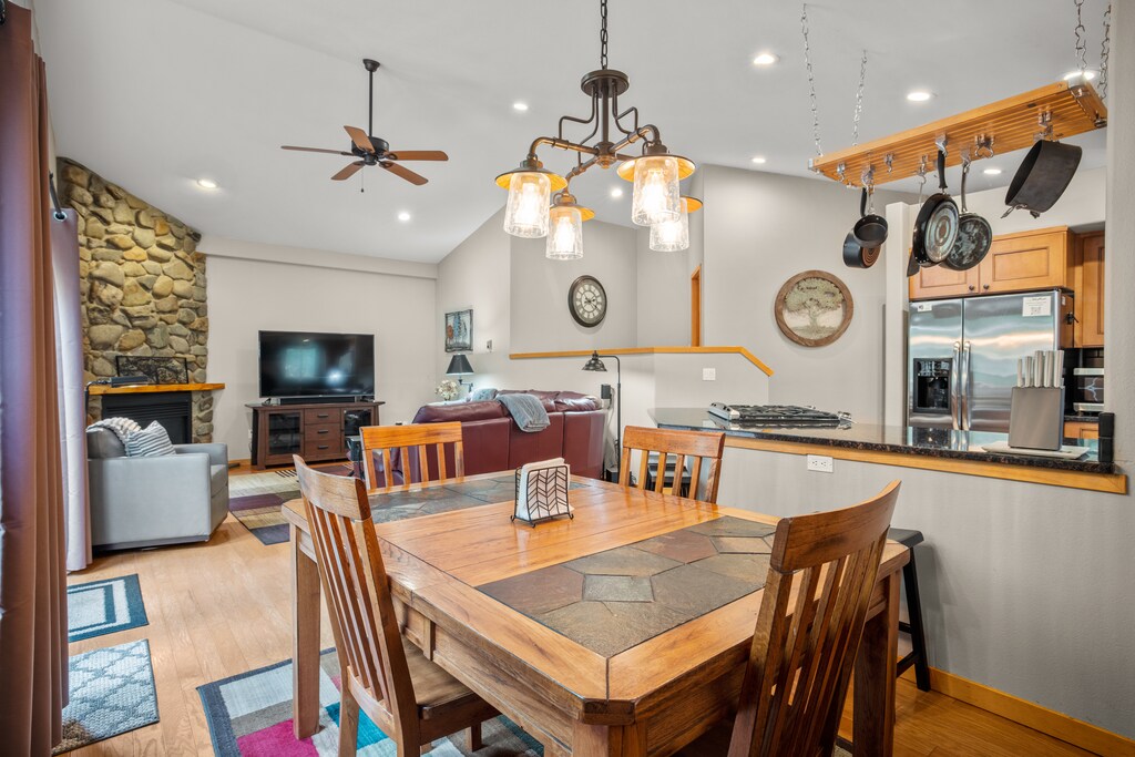 Rustic dining space featuring a wooden table for six, stylish overhead lighting, and an open view into the kitchen and living area. Ideal for family meals and entertaining.