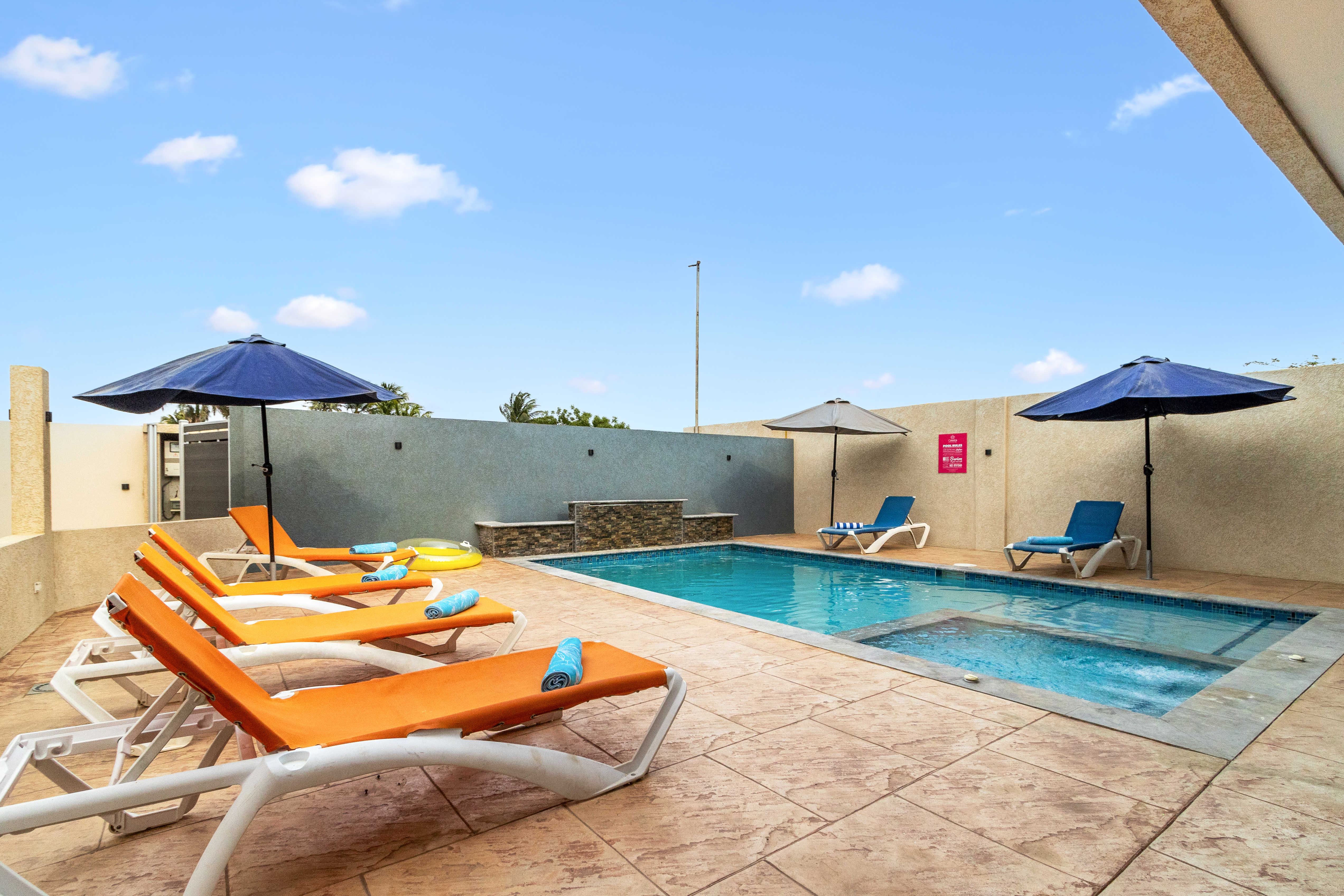 Refreshing shared pool area of the apartment in Oranjestad Aruba - With lounge chairs and a heated jacuzzi - Crystal-clear pool for refreshing dips - Sleek and stylish pool deck design