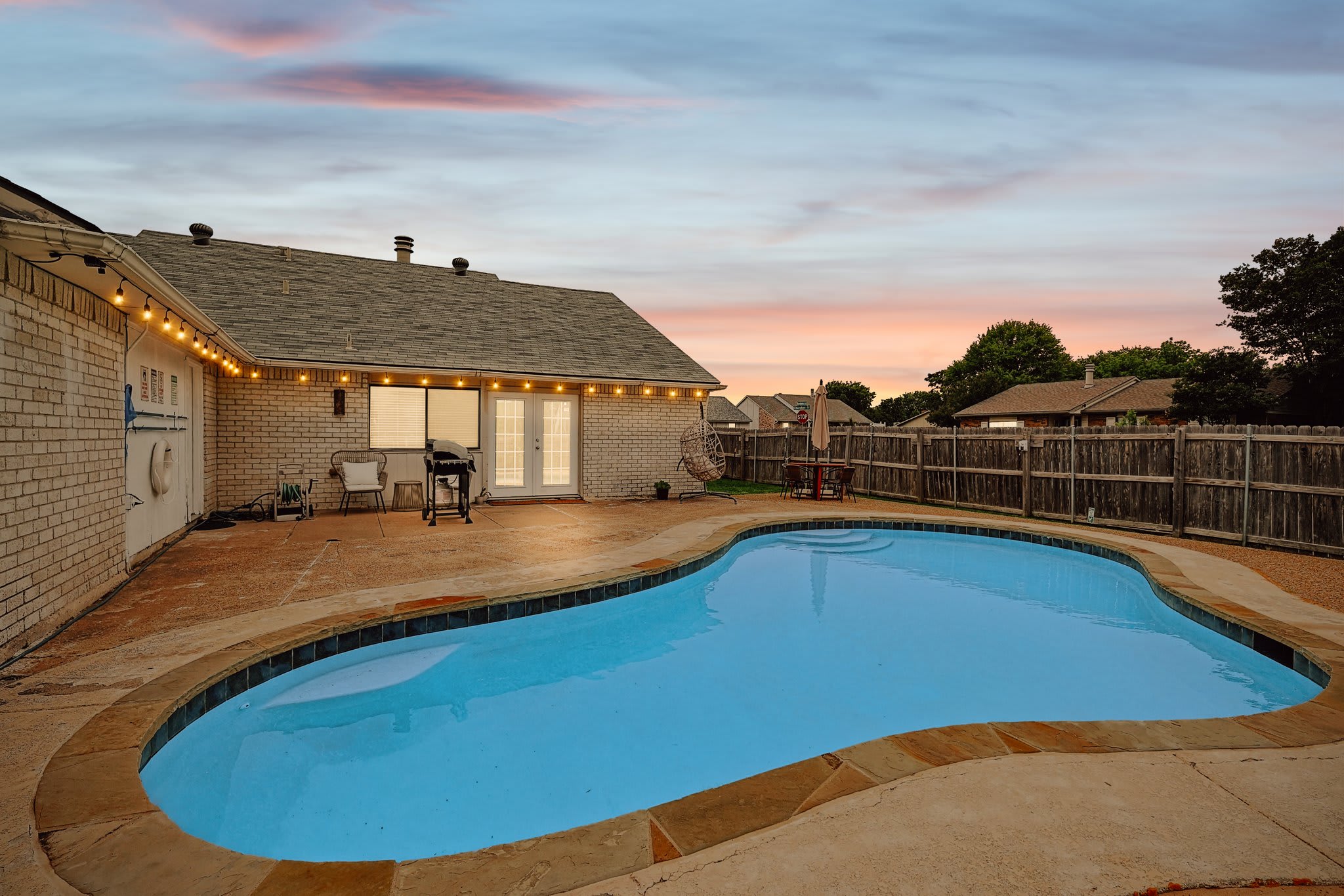 Come enjoy the best of indoor/outdoor living in this fully fenced backyard oasis featuring an outdoor swimming pool, patio, BBQ grill, swing chair, and more!