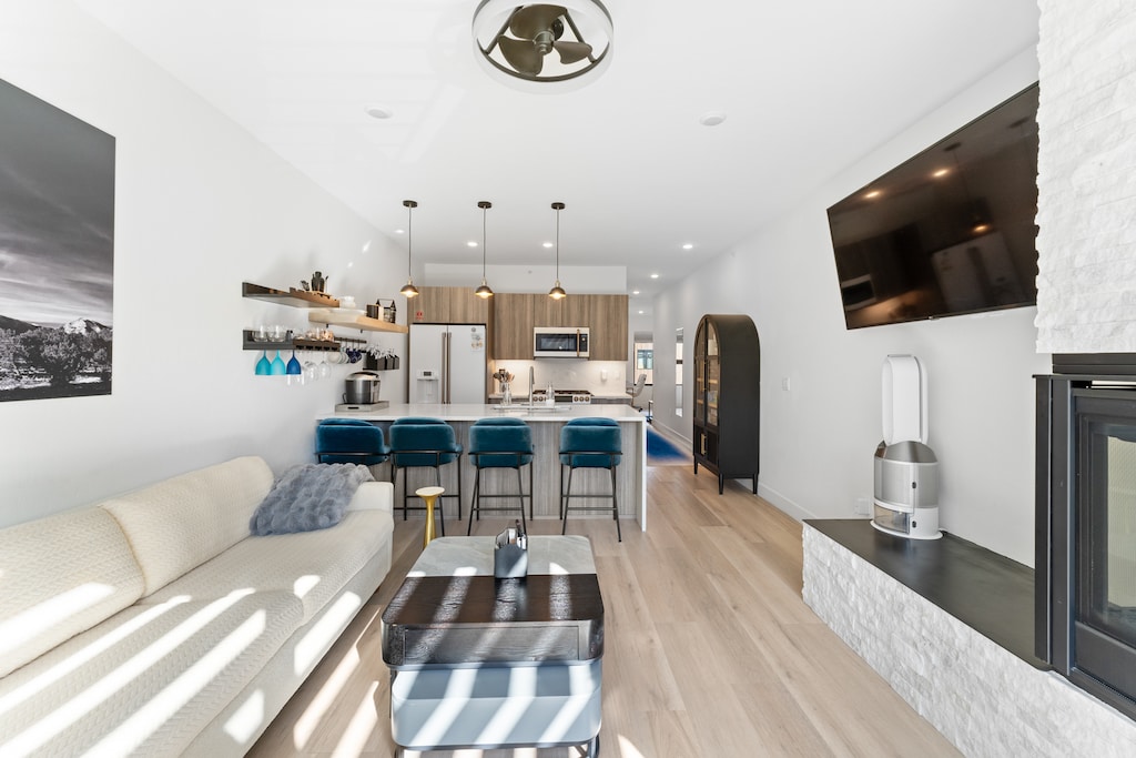 Open concept living area featuring a gas fireplace, flat screen TV, queen sleeper sofa, remote control blinds, and air purifier. 