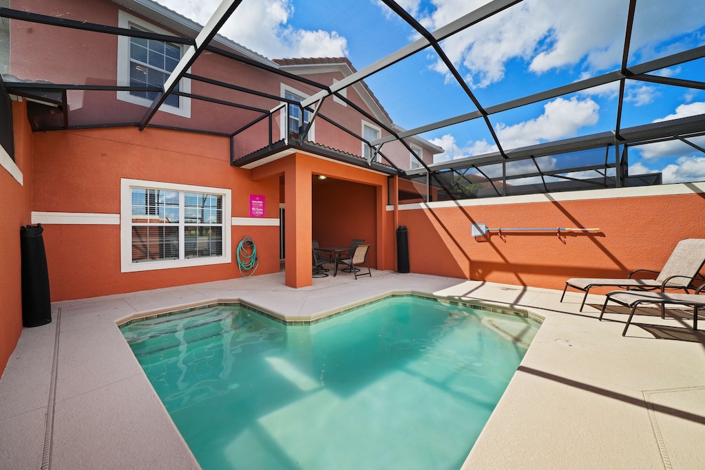 - Private pool area with a screened enclosure, perfect for swimming under the sun - Vibrant orange exterior walls add warmth and character to the space - Comfortable seating and lounge chairs create an ideal spot for outdoor relaxation and dining