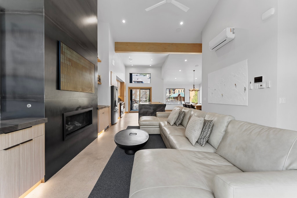 Open-concept living area featuring a mounted TV over a gas fireplace, balcony access, and dry bar with wine fridge. 