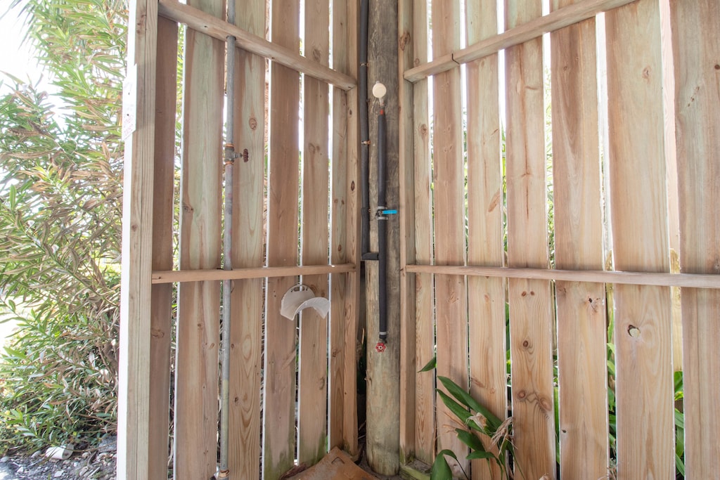 Your private outdoor shower awaits, surrounded by natural wood and lush tropical plants for a refreshing, secluded bathing experience.