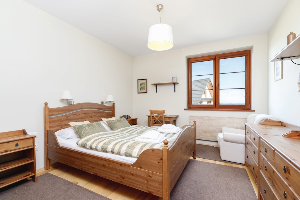A neatly arranged bedroom with twin beds, bedside tables, and a window allowing natural light.