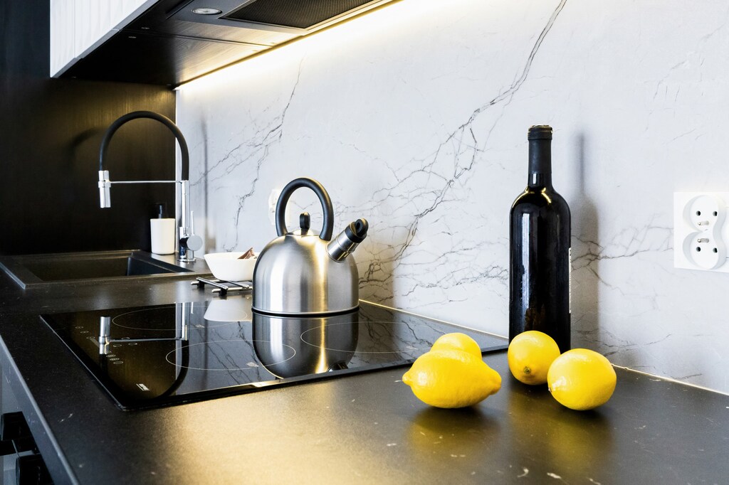 A close-up of the kitchen counter with a kettle, a bottle of olive oil, and fresh lemons displayed as decor.