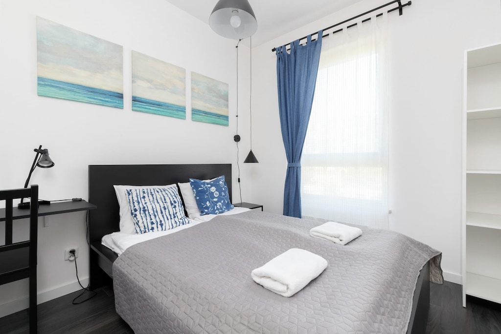 A cozy bedroom featuring a double bed, blue-themed decor, and bedside tables with lamps.