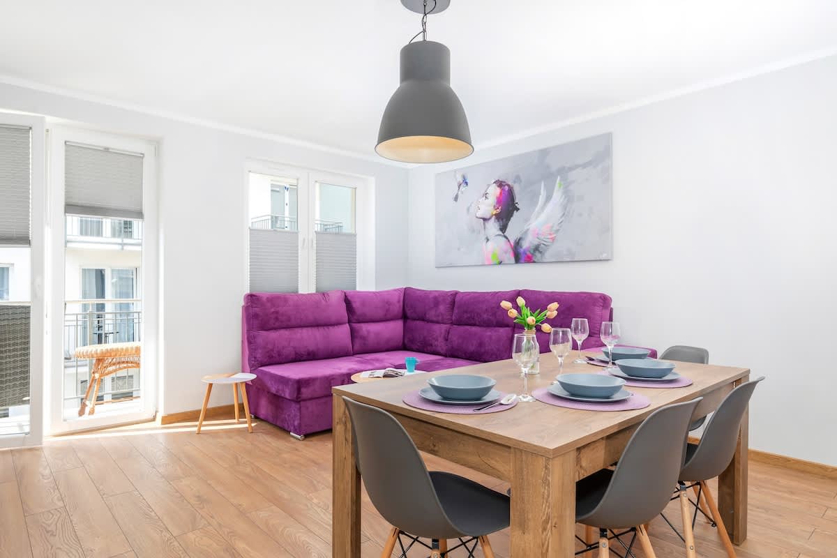 Living room with a TV, fold-out sofa bed, dining area and exit to balcony.