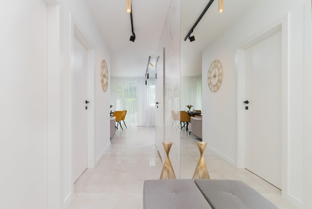 Long, minimalist corridor with white walls and light flooring.