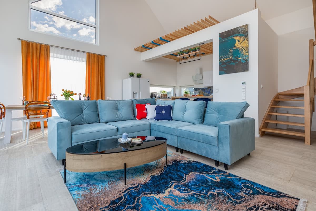 A bright and modern living room with a large blue sofa, colorful curtains, and a neatly designed space.