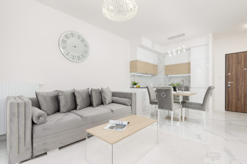 A luxurious living and dining area with a grey sectional sofa, elegant dining chairs, and marble-patterned flooring, creating a sophisticated ambiance.
