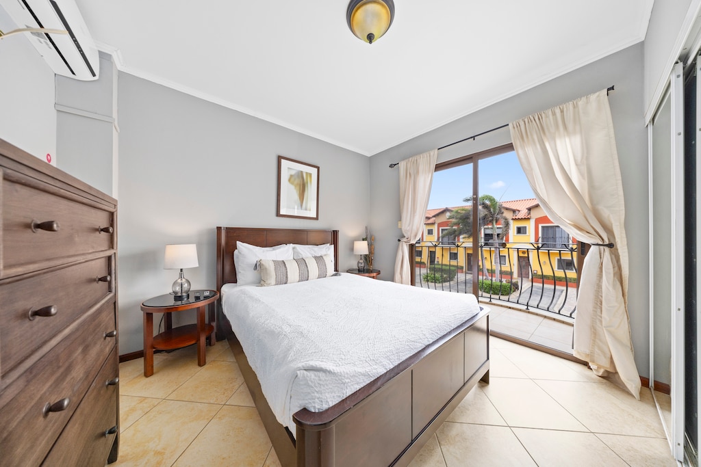 - Enjoy a peaceful retreat in the cozy bedroom of the townhouse in Noord, Aruba. - The bedroom features direct access to a balcony. - This bedroom offers a cozy bed and tasteful decor. - Wake up to beautiful views and fresh breezes from the balcony.