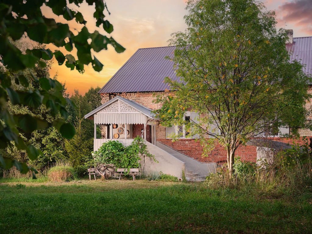 The house surrounded by greenery, showcasing its red brick exterior and idyllic countryside charm.