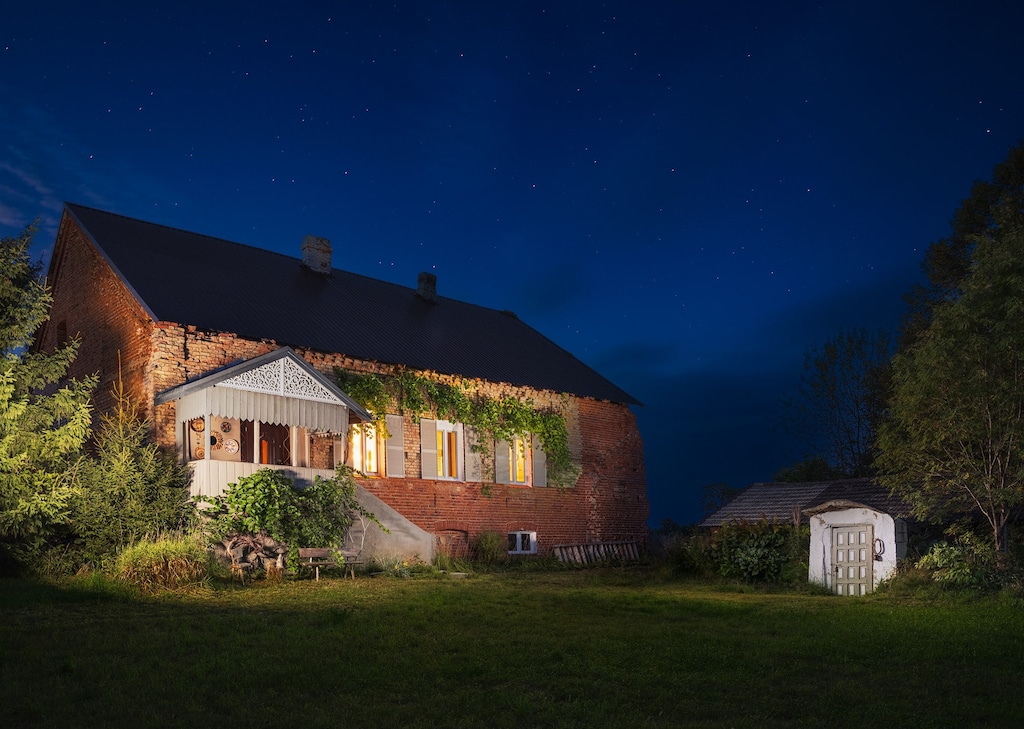 The house surrounded by greenery, showcasing its red brick exterior and idyllic countryside charm.