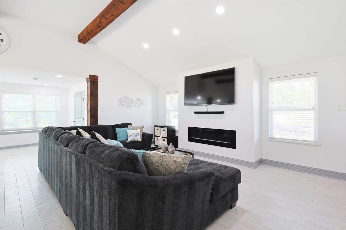 Featuring arched ceilings, an oversized U-shaped sectional, and beautiful rustic wooden arches, this living room exudes an atmosphere of comfort and relaxation.