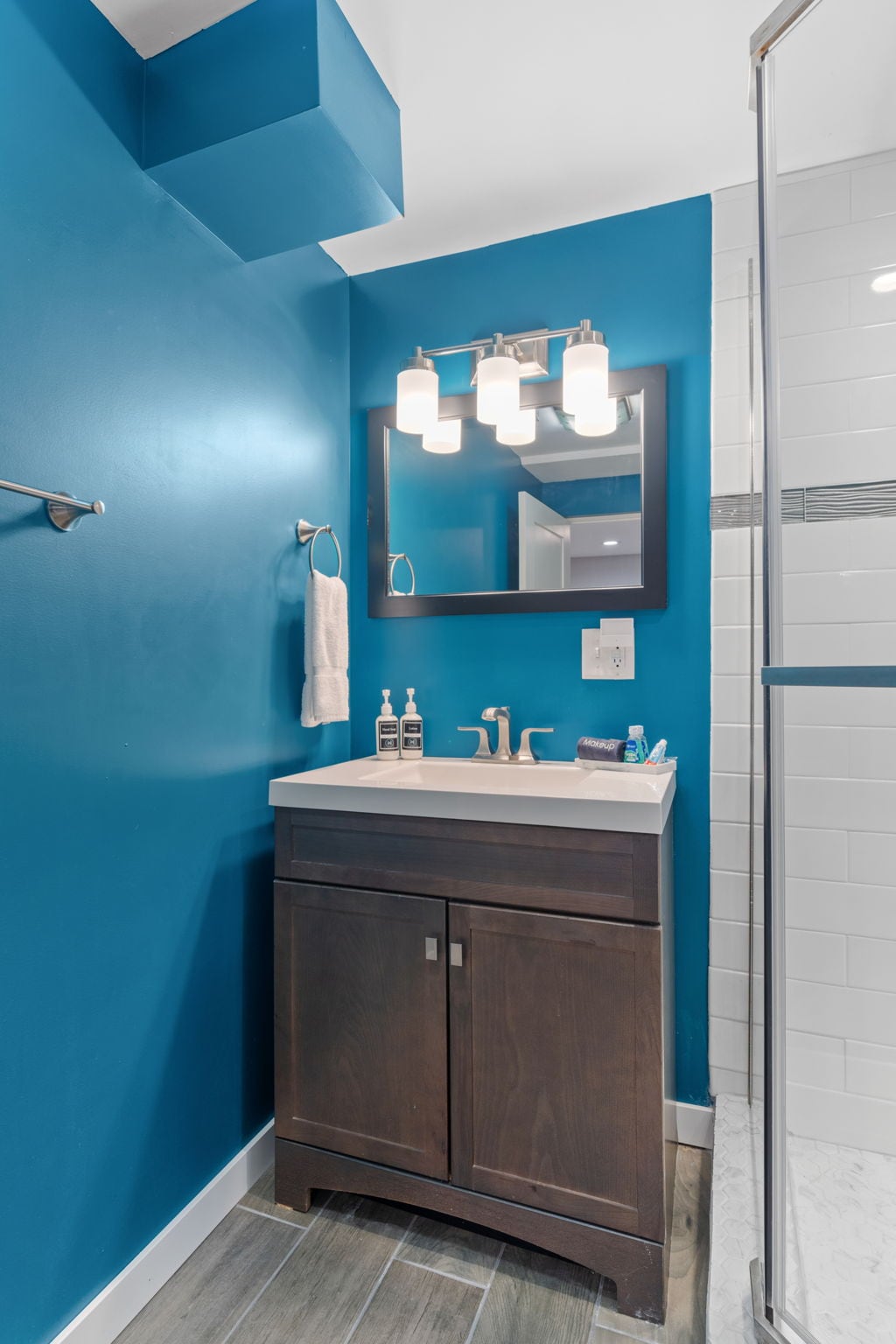 Refresh in your vibrant bathroom featuring bold blue walls, modern vanity, and bright lighting.