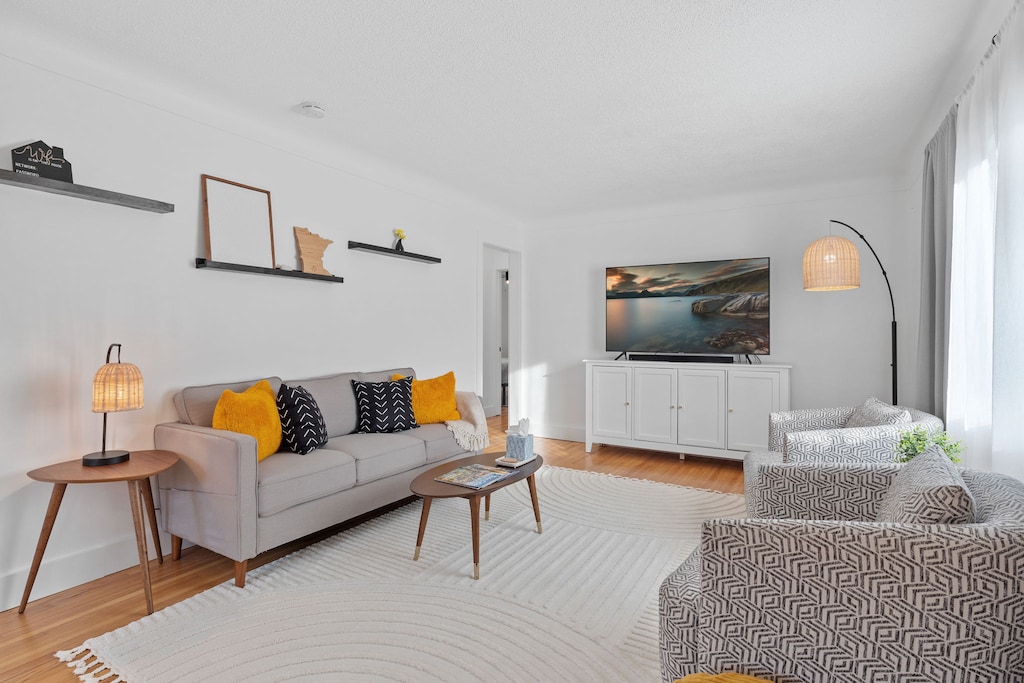 Sink into plush seating with vibrant accents while streaming your favorite shows on the large TV in this bright, modern living space.