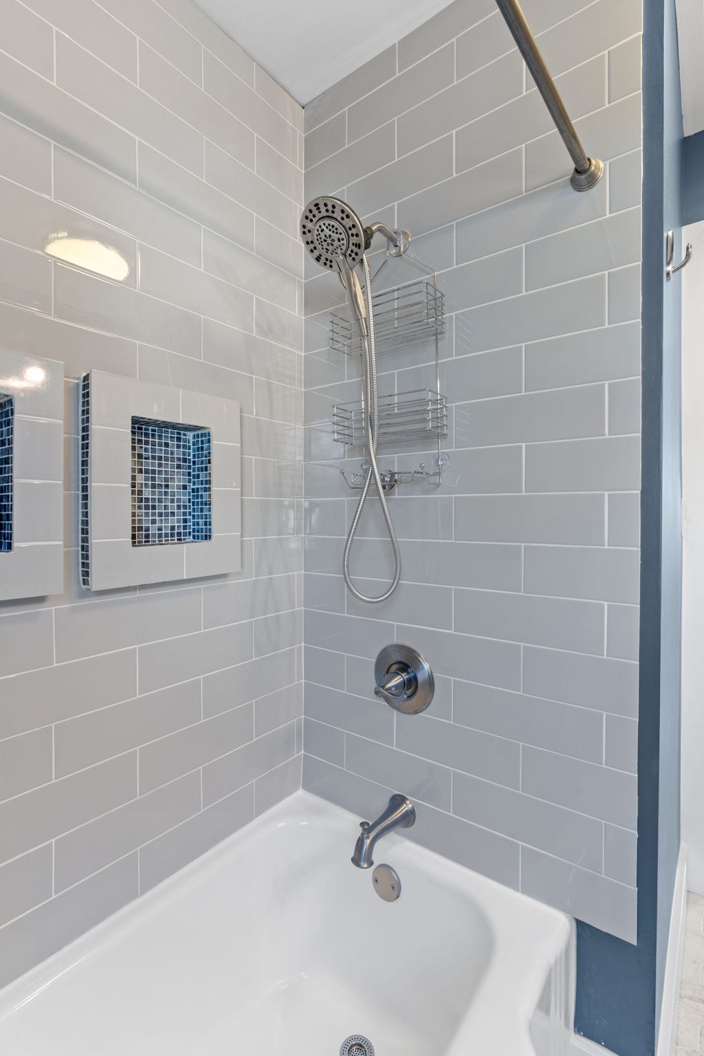 Refresh in your private tub-shower combo featuring sleek gray subway tiles, built-in shelving, and thoughtful storage niches.