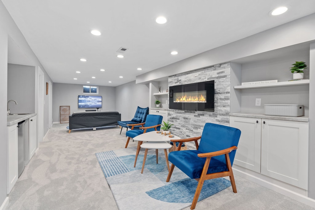 Unwind in your stylish lower level retreat featuring a cozy fireplace, modern blue chairs, and entertainment space for relaxing evenings.