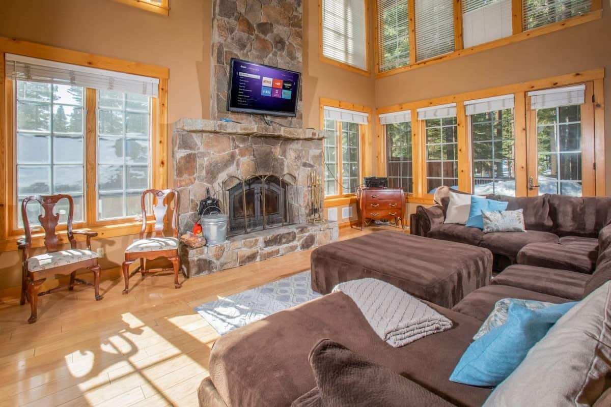 Relax in the spacious living room where you will find soaring ceilings and windows, a mounted flatscreen TV, a beautiful stone hearth fireplace, and a large comfortable sectional sofa.