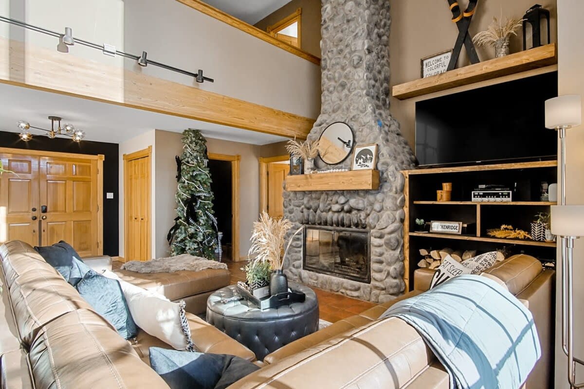 Relax in the luxurious leather sofa with a cozy wood-burning fireplace, a large flat-screen TV, and stunning forest views through the expansive windows