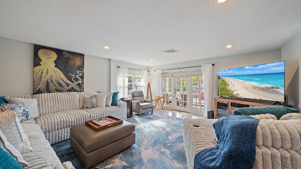 Spacious living room with a sectional sofa, a large octopus art piece, a flat-screen TV, and access to a patio.