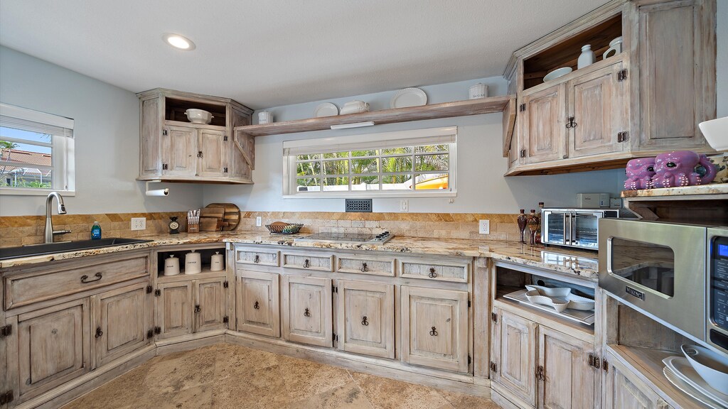 Rustic-style kitchen with a built-in cooktop, a countertop toaster oven, a Viking microwave oven, an undermount sink, and distressed wood cabinets.