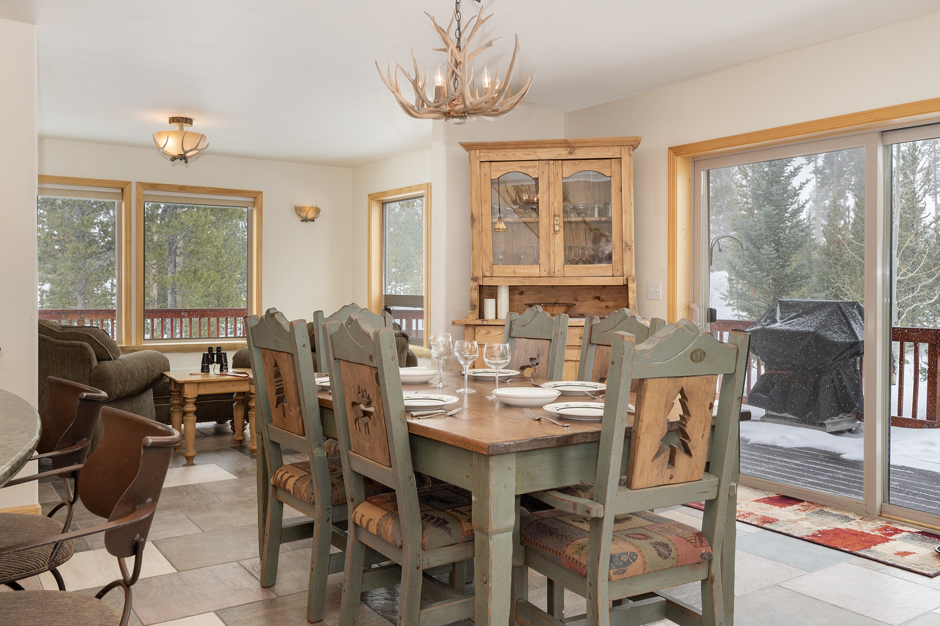 Rustic dining table with large windows bathing the space in natural light and lovely views