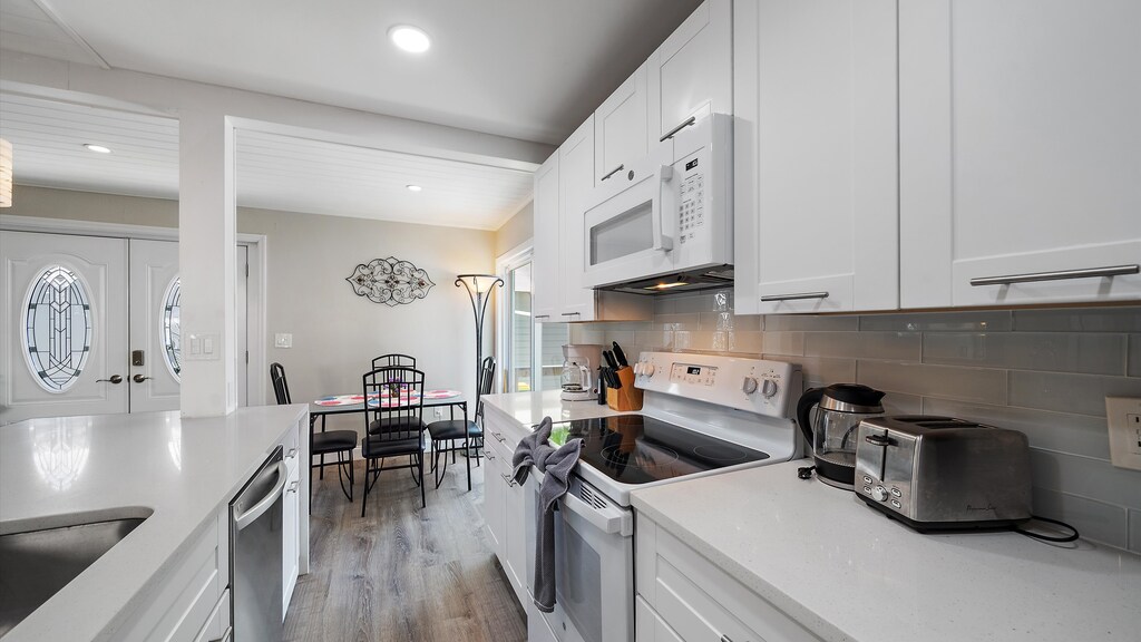 Bright kitchen with white cabinets, stainless steel appliances, and a dining table.