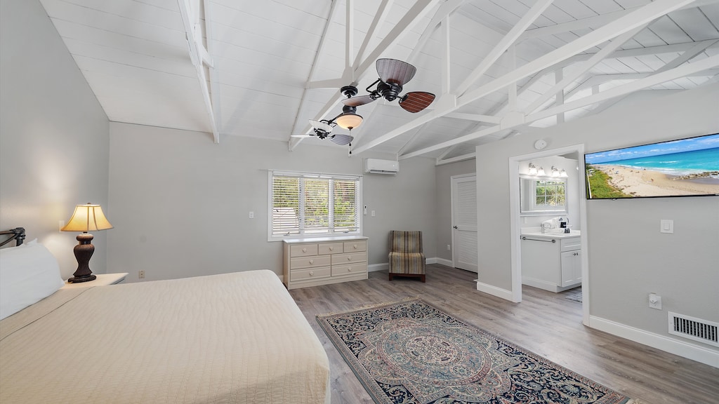 Primary Bedroom with wood-style flooring with a patterned area rug, and a bathroom with a white vanity and sink