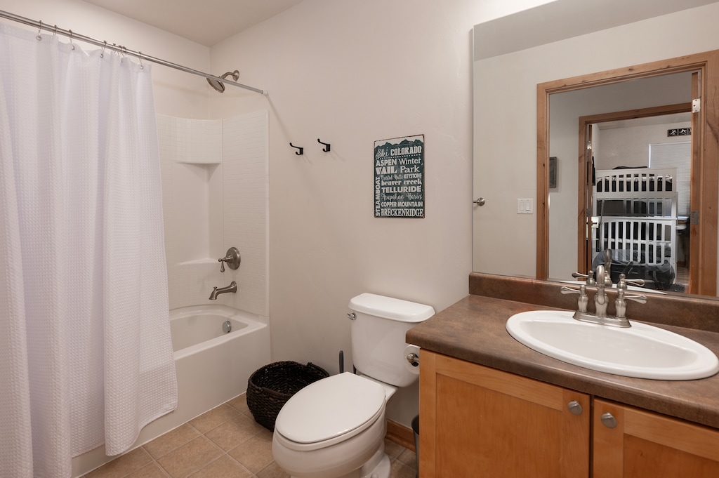 - Full bathroom with shower tub combo, soft lighting, and rustic wood vanity - Clean design includes towel hooks, storage space, and a framed mirror - Perfect for refreshing after a hike or preparing for a day out exploring