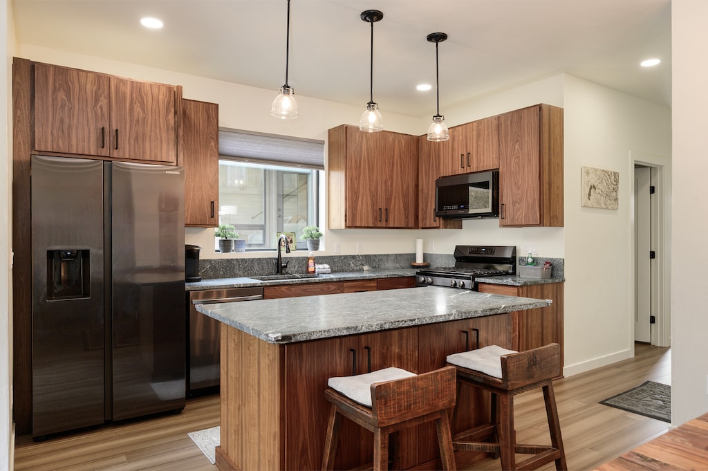 - Spacious kitchen with granite island and pendant lighting overhead   - Stainless steel appliances and wood cabinetry for modern convenience   - Perfect space for cooking meals and enjoying time together at home