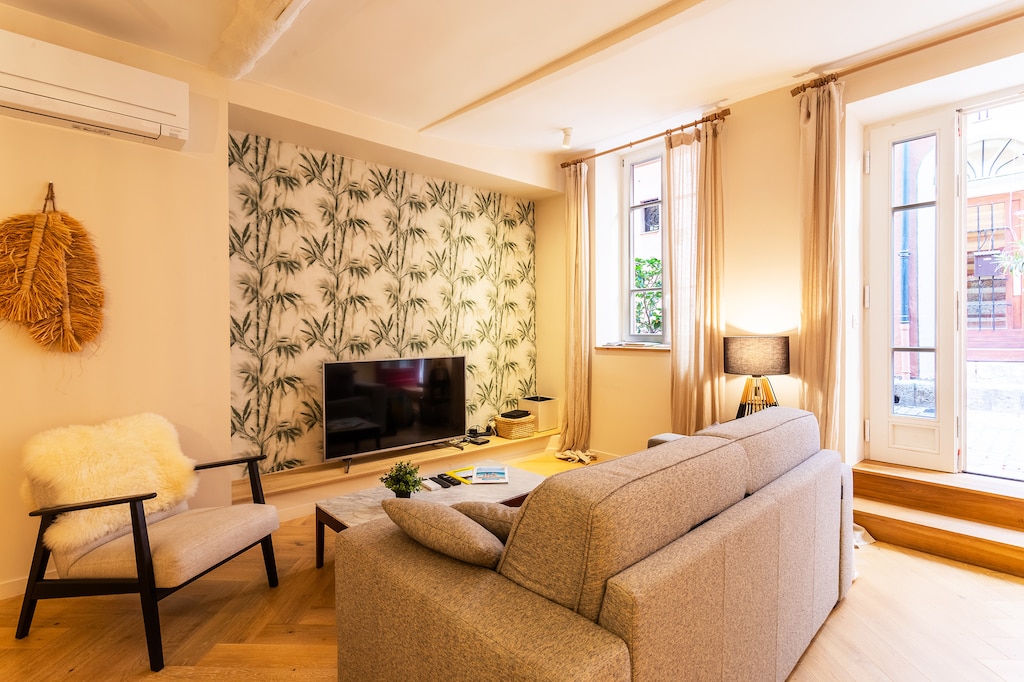 The main living room has a double sofa bed, TV, and a cozy, bright atmosphere.
