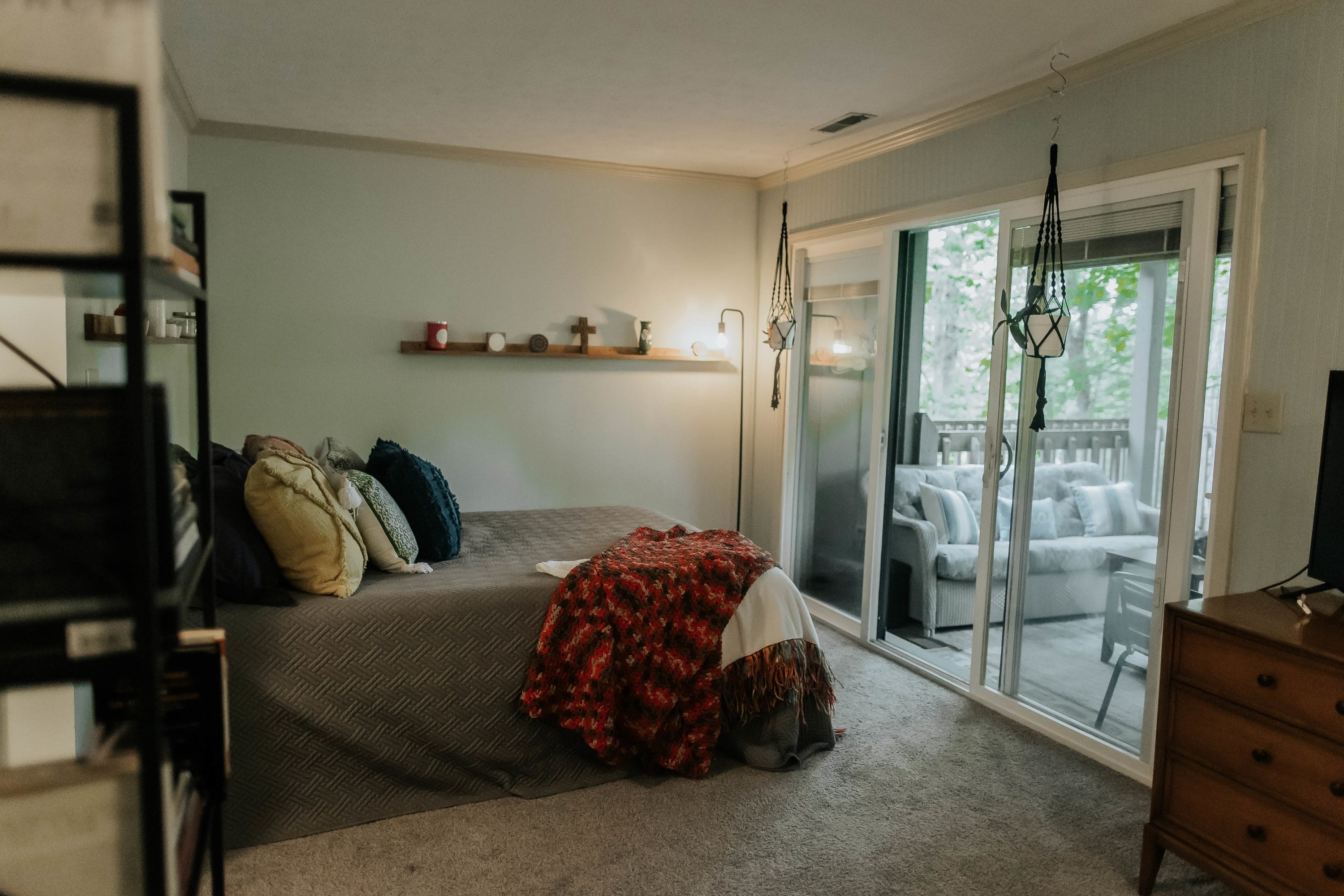 This cozy bedroom is thoughtfully decorated, featuring comfortable beds and pillows, a bookshelf, TV, and dresser, with direct access to the patio.